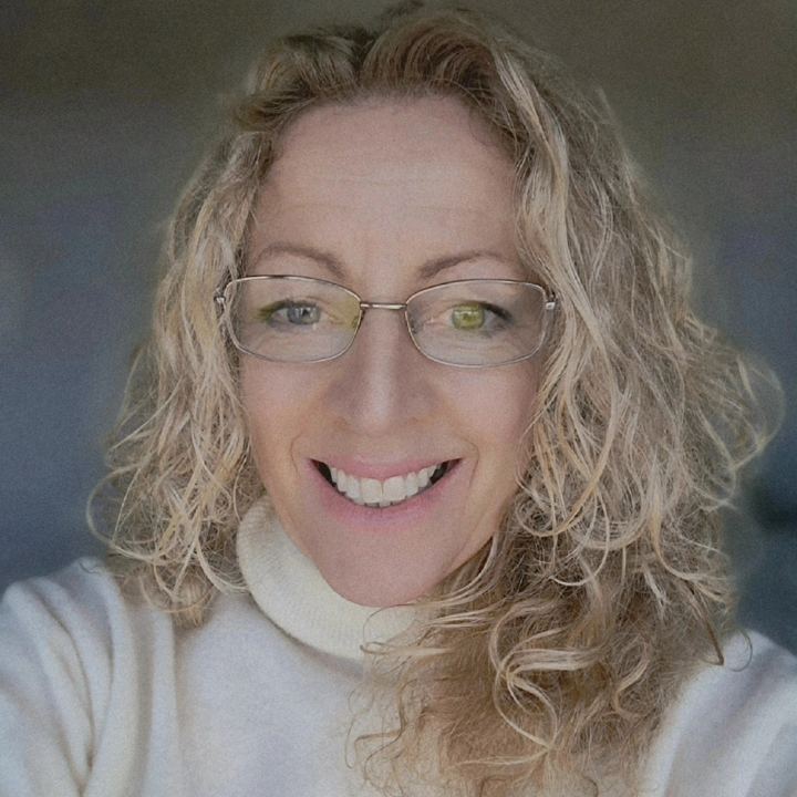 Clare Fitzgerald, smiling, with curly blonde hair and glasses